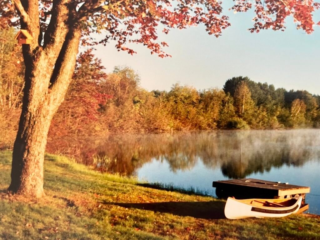 Still lake with mist and autumn colours with a canoe in the foreground